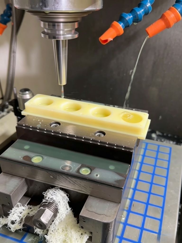 Precision plastic CNC machining process milling a custom engineered polymer component with coolant flush.